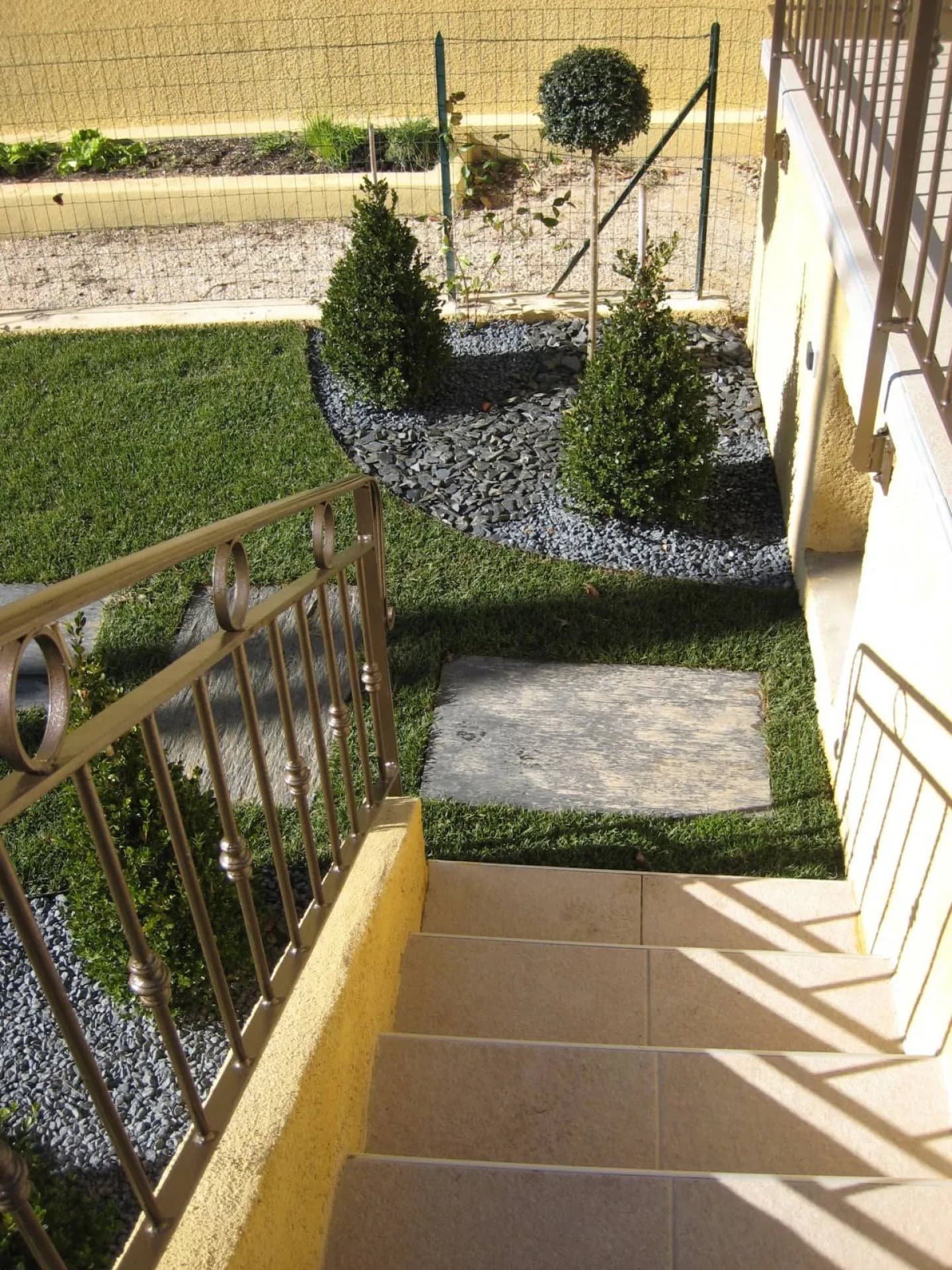 Petit jardin structuré : buis, paillage d’ardoise, pas japonais dans le gazon et escalier carrelé