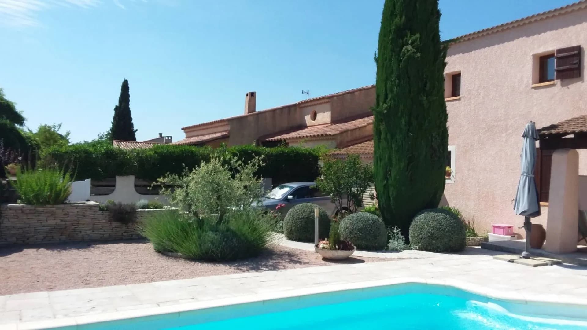 Jardin sec de villa au bord de la piscine : lavandes, boules taillées, olivier et muret de pierre
