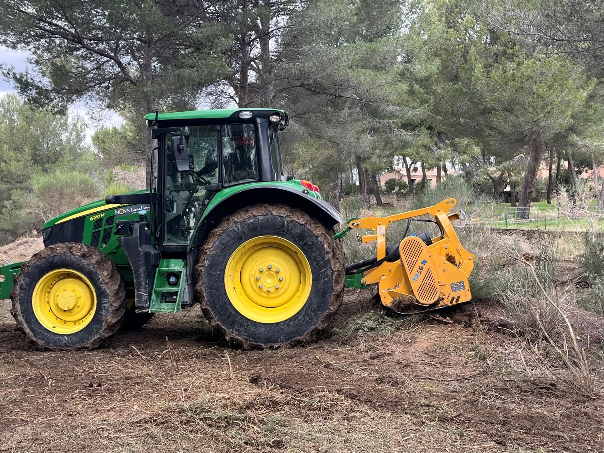 Vue latérale du tracteur 130 cv et du roto-broyeur en action dans une pinède à Velaux, sol broyé net